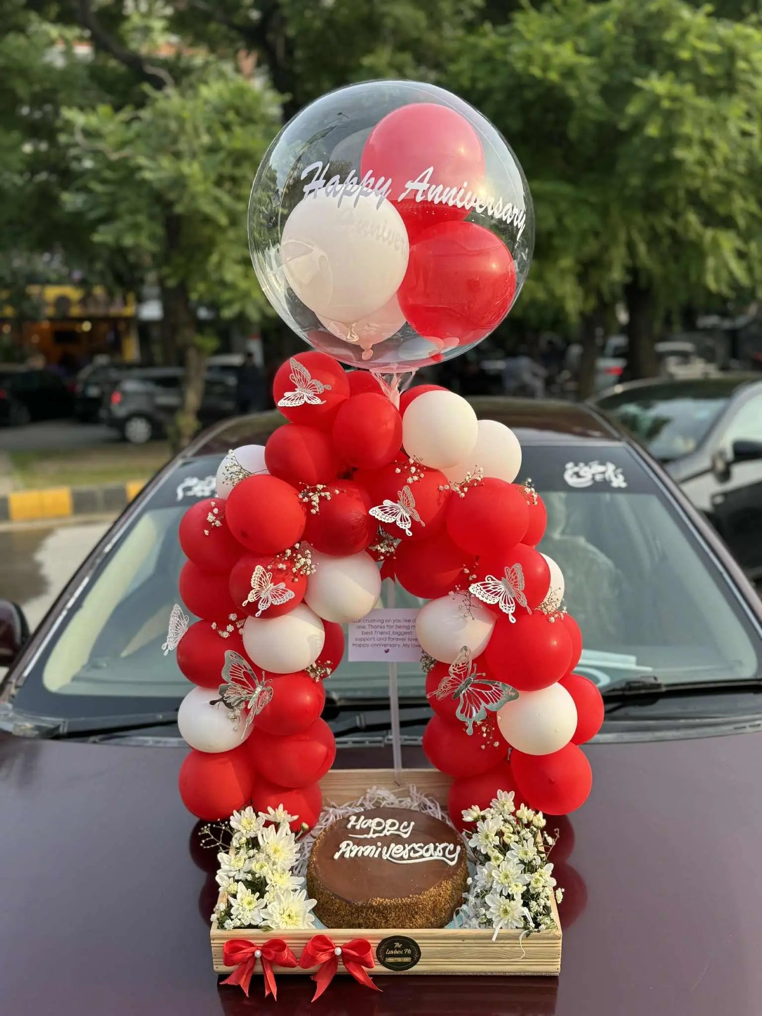 Anniversary wooden tray with balloon arch, fresh flowers, and cake in Islamabad