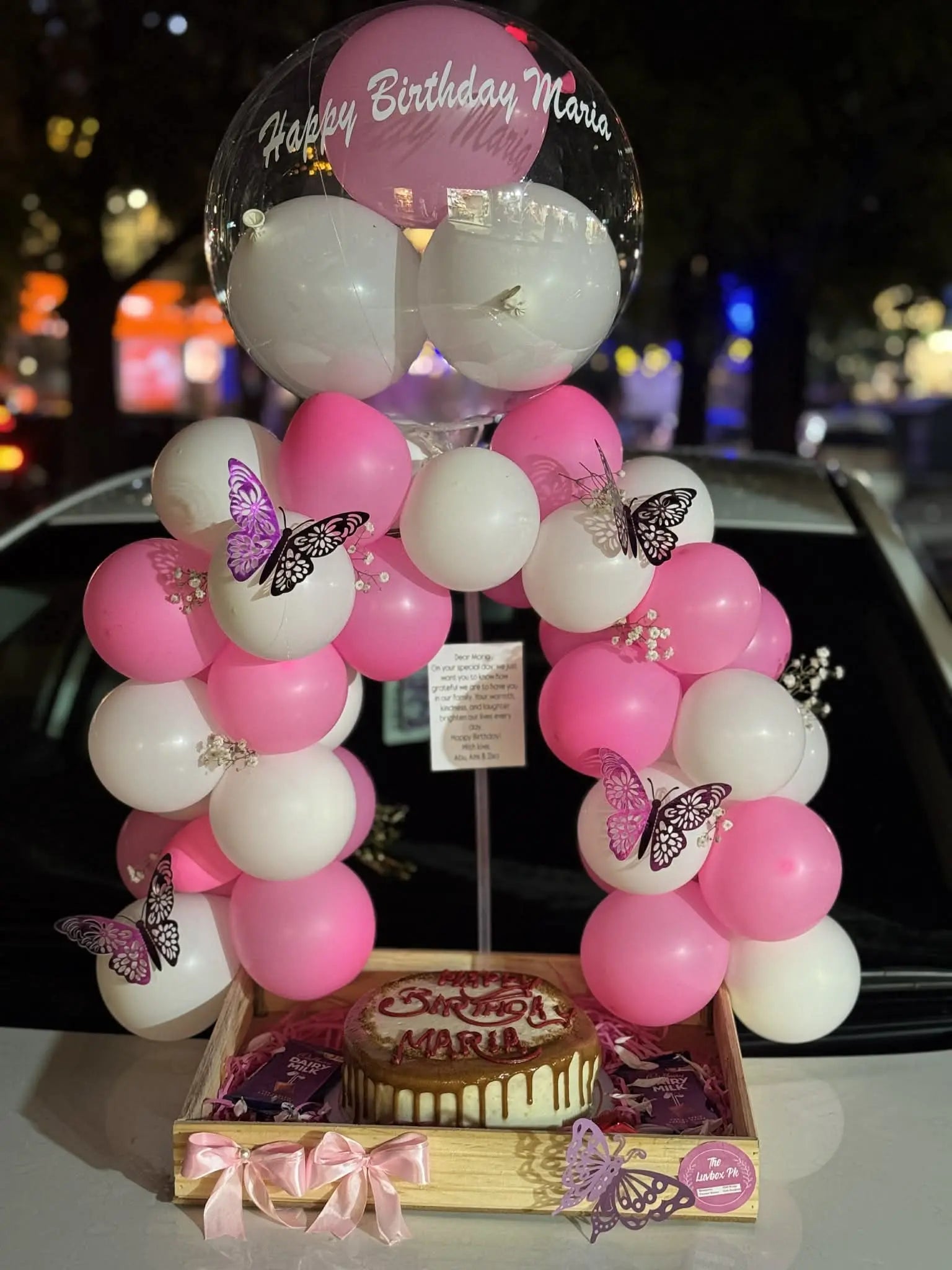 Gorgeous balloon arch with cake placed in wooden basket for stylish birthday gift delivery in Islamabad.