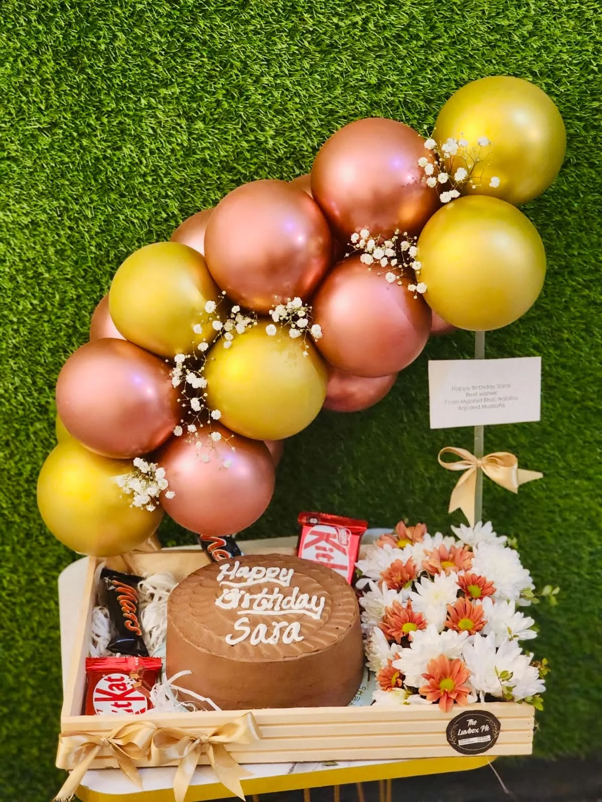 Birthday gift for her with Layers Bakery chocolate cake flowers chocolates and balloon arch on wooden tray