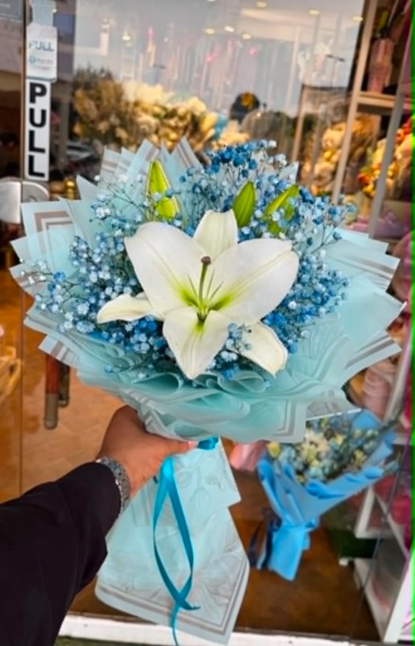 Mini white lily bouquet for him with blue Baby’s Breath and elegant blue wrapping, perfect for birthdays and special occasions in Islamabad.