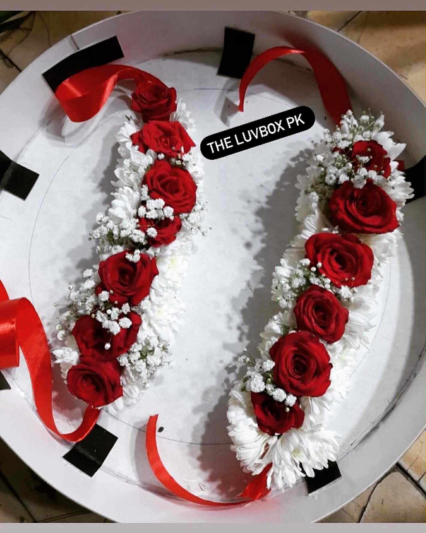 Floral gajray pair in white chrysanthemum, red roses, and baby’s breath – elegant hand jewelry for weddings in Islamabad, Pakistan.