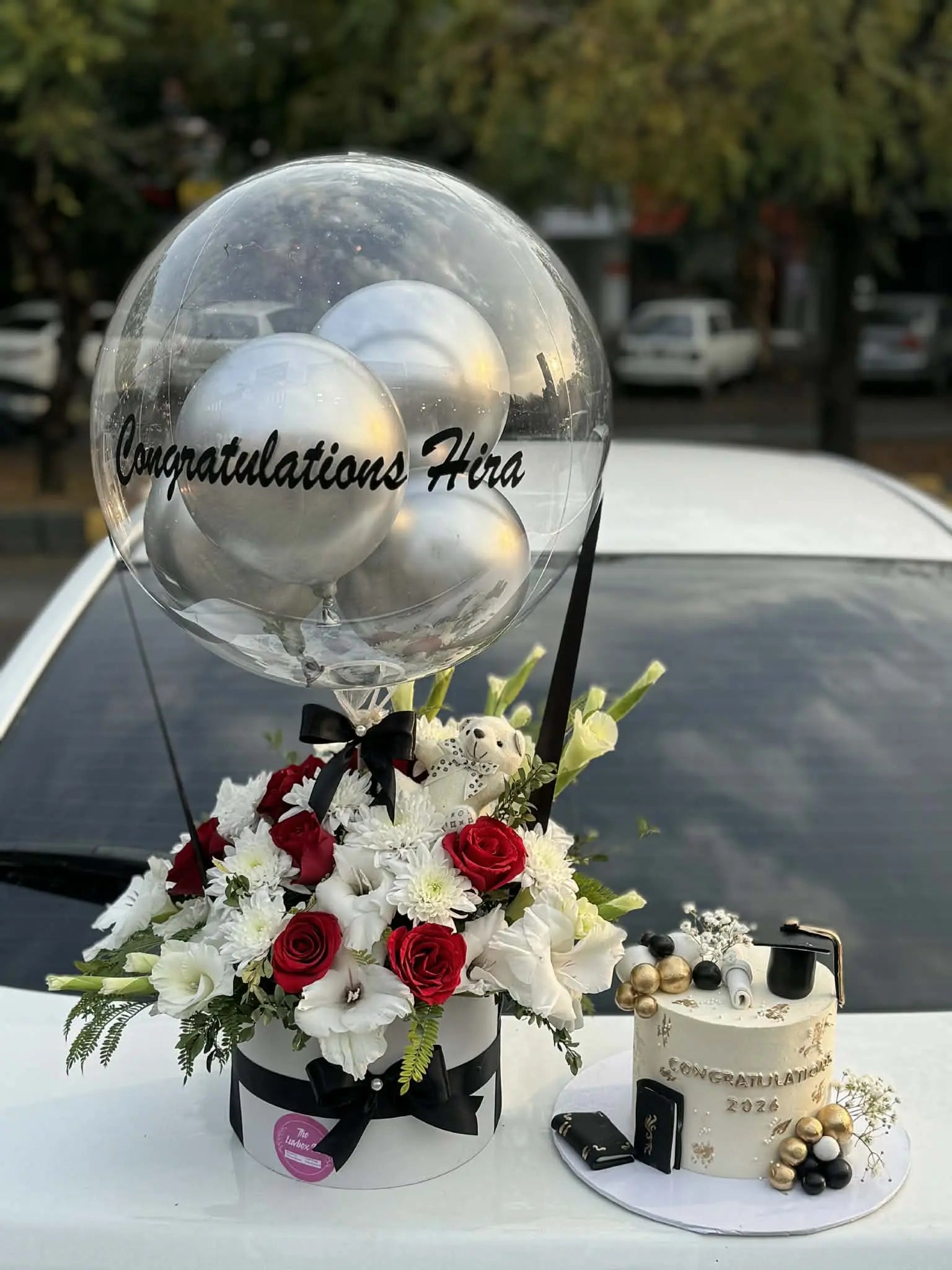 Graduation combo with white gold black themed cake and flower balloon box from gift shop Islamabad
