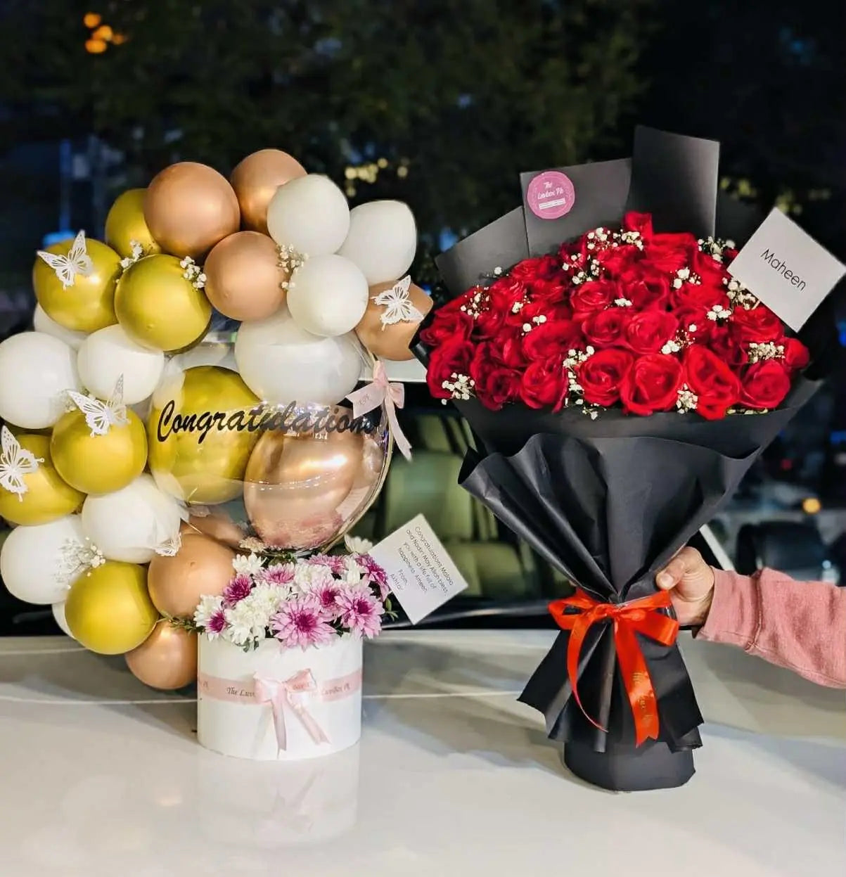 Congratulations-themed balloon arch with red rose bouquet
