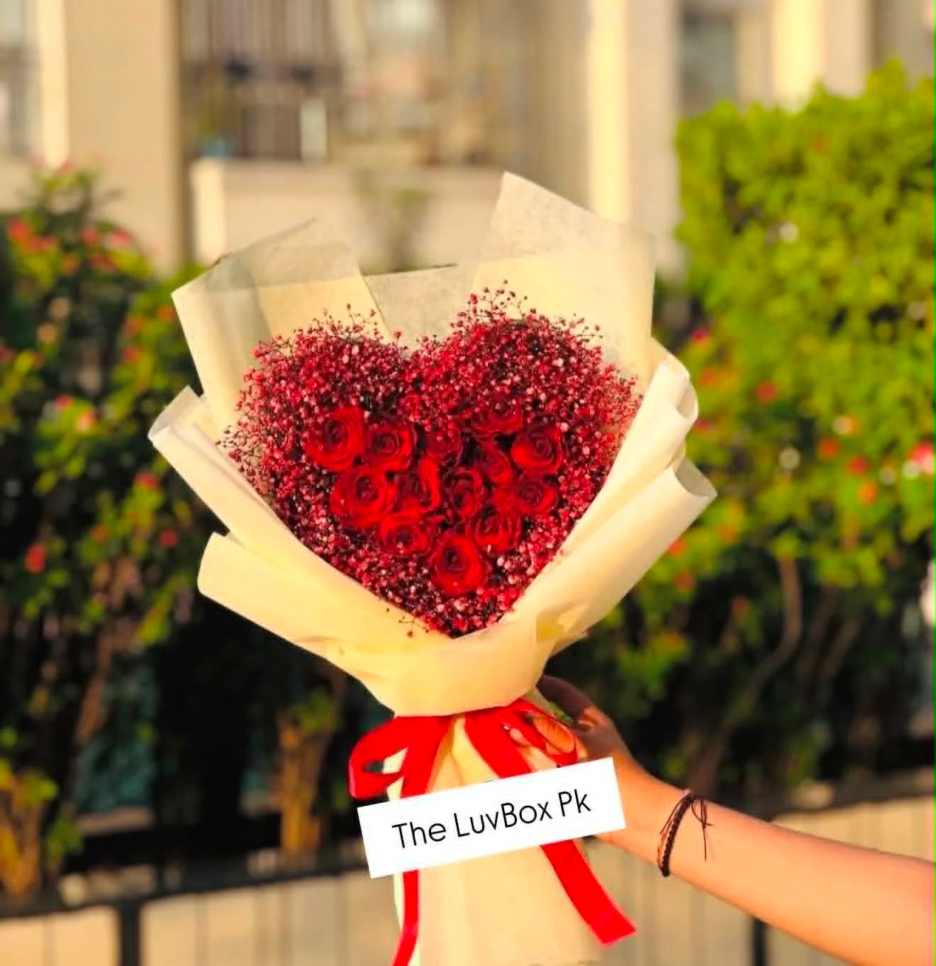 Beautiful heart-shaped flower box with roses in the center, Baby’s Breath around the flowers, and elegant white wrapping for flower delivery in Islamabad.