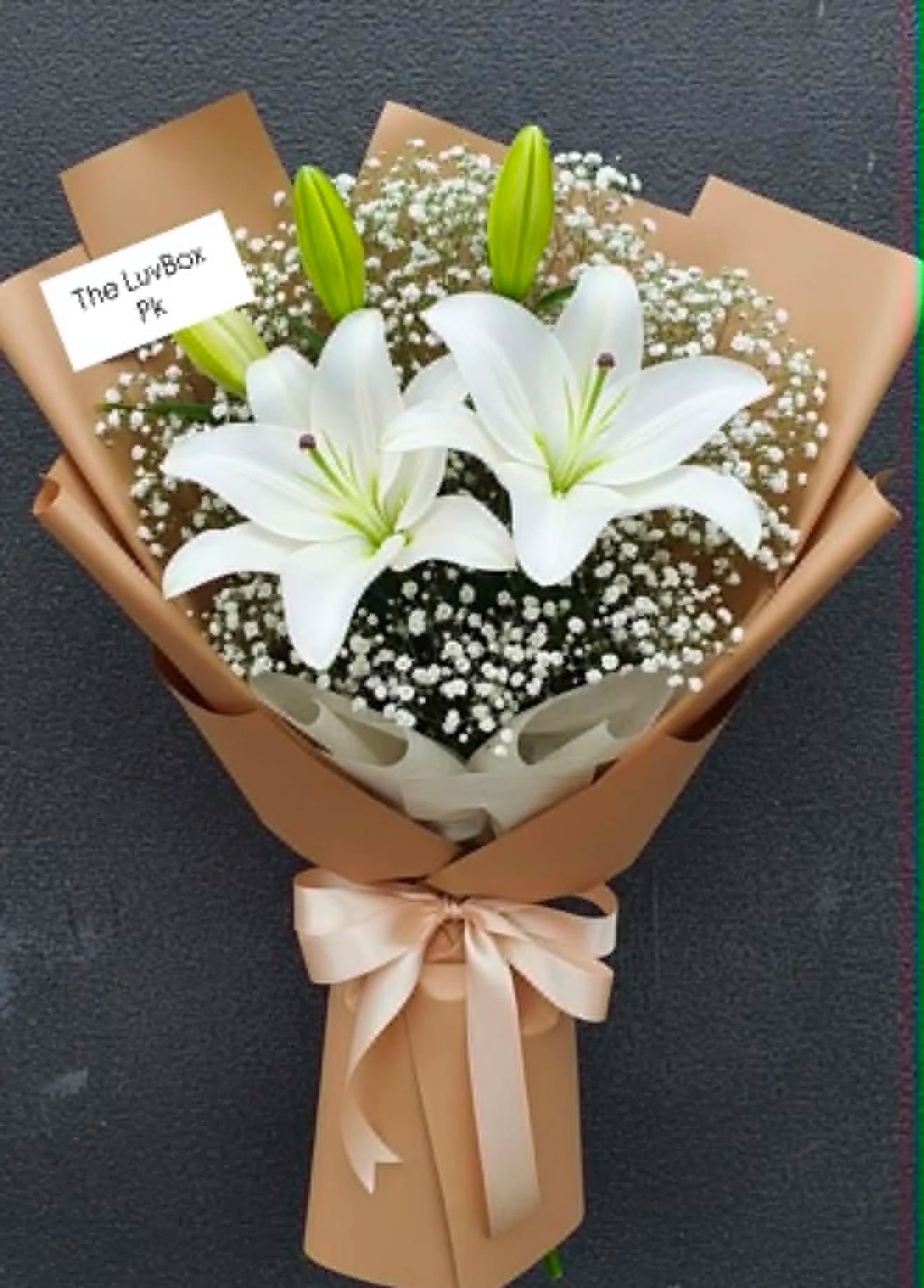 Gorgeous mini bouquet of fresh white lilies elegantly wrapped in brown, perfect for birthdays, anniversaries and flower delivery in Islamabad.