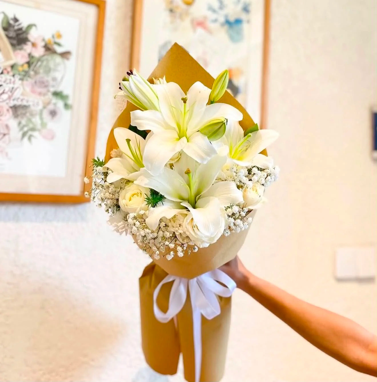 Beautiful bouquet of fresh white lilies elegantly wrapped in brown paper, perfect for birthdays, anniversaries and flower delivery in Islamabad.