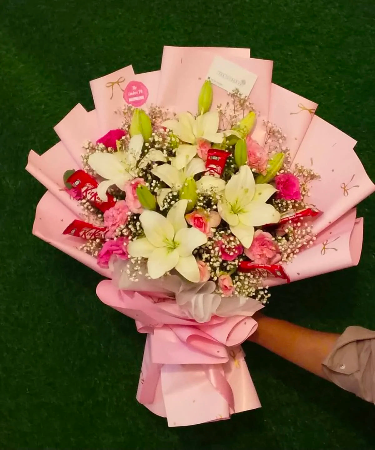 Beautiful white lily bouquet with KitKat chocolates, elegantly wrapped as a unique flower and chocolate gift for birthdays and special occasions in Islamabad.