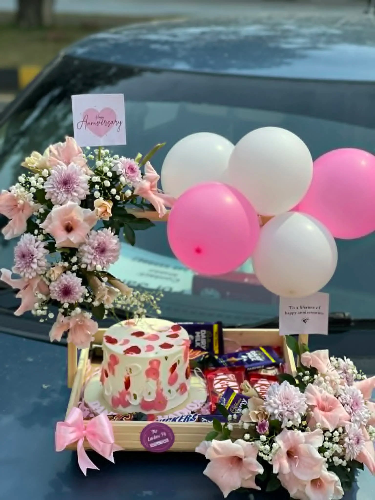 Luxury anniversary wooden tray with cake, flowers, balloons, lights and chocolates in Islamabad.