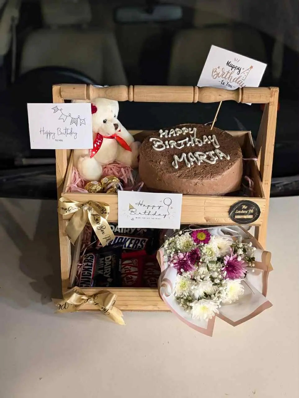 Double wooden basket filled with cake, chocolates, and flowers