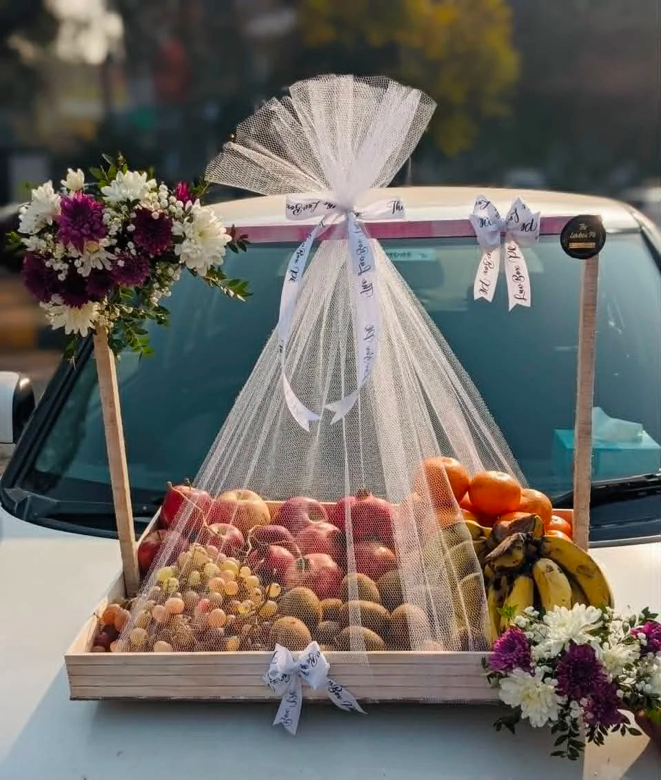 Luxury wedding fruit basket with 6–8 kg mixed seasonal fruits, elegant flower decorations, and premium net wrapping for Shaadi Mubarak and engagement gifts in Pakistan.