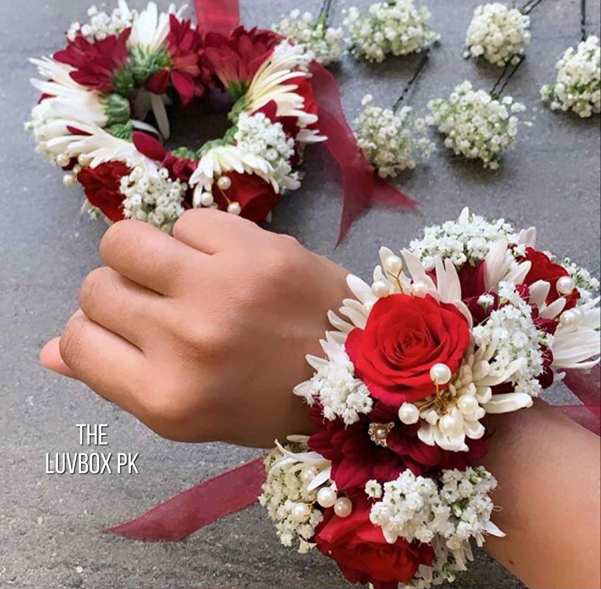 Red rose and white chrysanthemum hand gajray pair for brides in Islamabad, Pakistan.