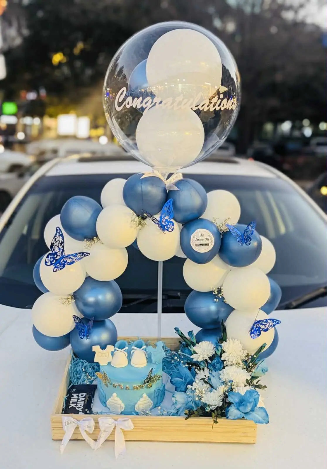 Baby boy celebration basket with cake, balloon arch, flowers in wooden basket