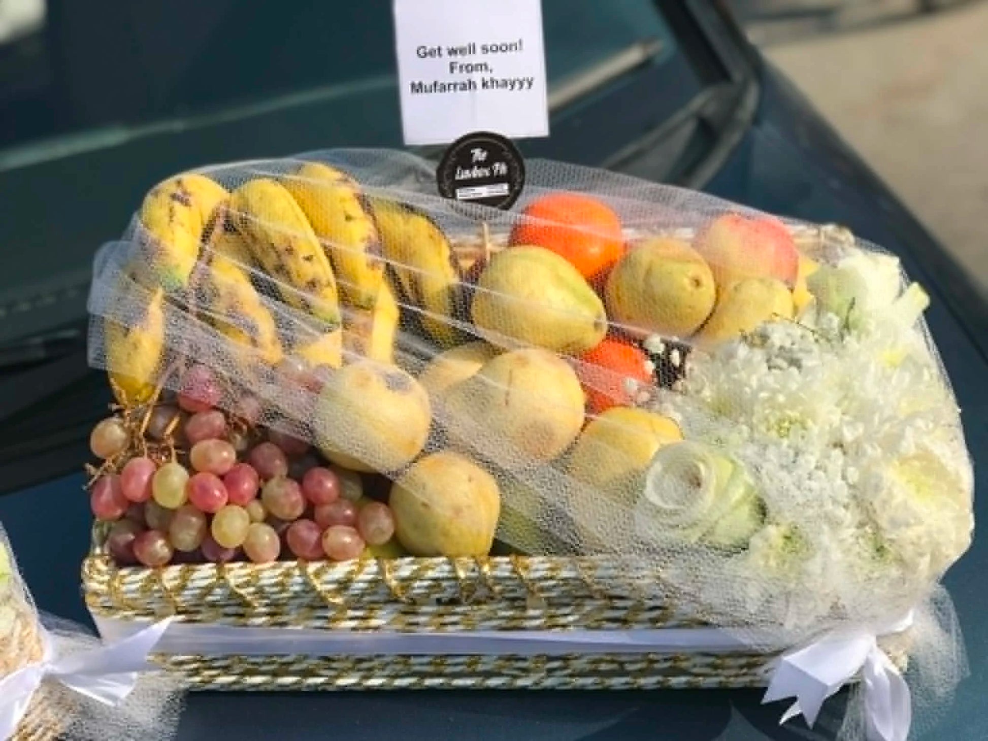 Luxury wedding fruit basket with 6 to 8 kg mixed seasonal fruits, white flower decoration, and premium net wrapping for Shaadi Mubarak gifts in Pakistan.