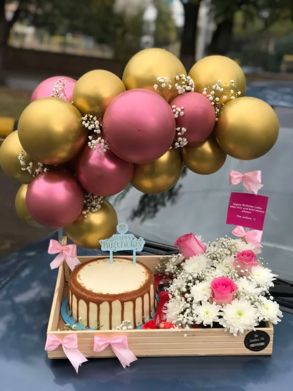 Cute wooden tray with balloon arch, cake, flowers, and chocolates by The LuvBox PK – gift shop in Islamabad